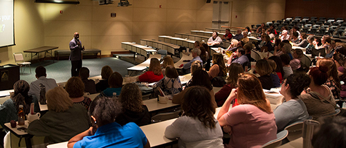 Faculty and staff listen to a presenter in a lecture hall.
