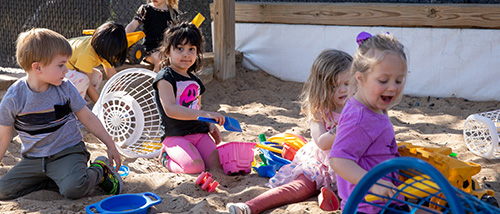 A group of children play in the sand outside